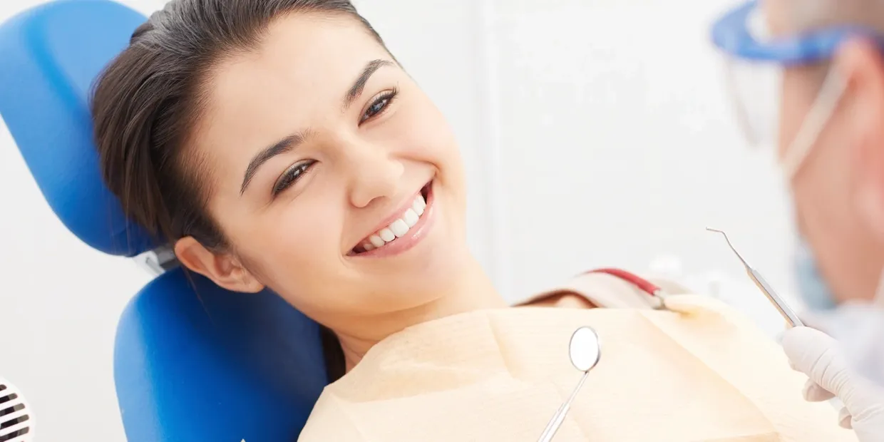 A woman smiling while sitting in the dentist chair.