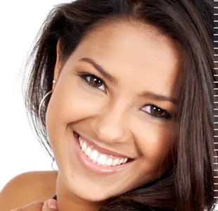 A woman with brown hair and white teeth smiling.